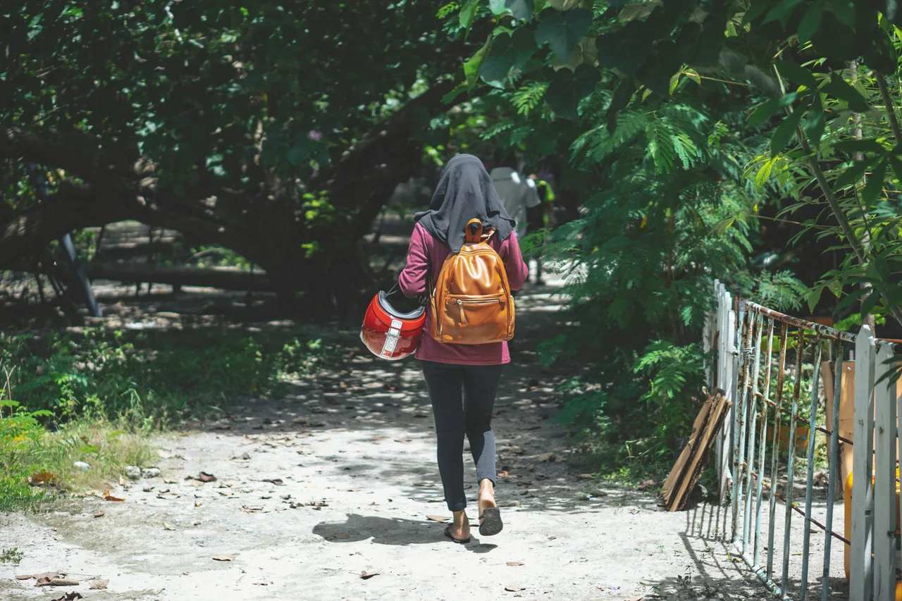 A traveller walking away along a leafy Maldivian island path
