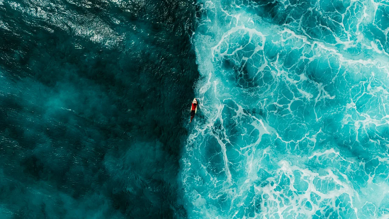 A surfer riding a breaking wave in the Maldives