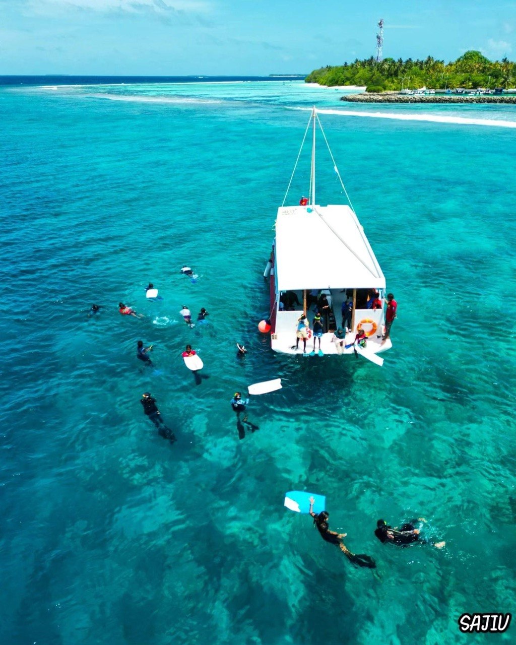 Moodhu Bulhaa dive boat and swimmers in a turquoise lagoon