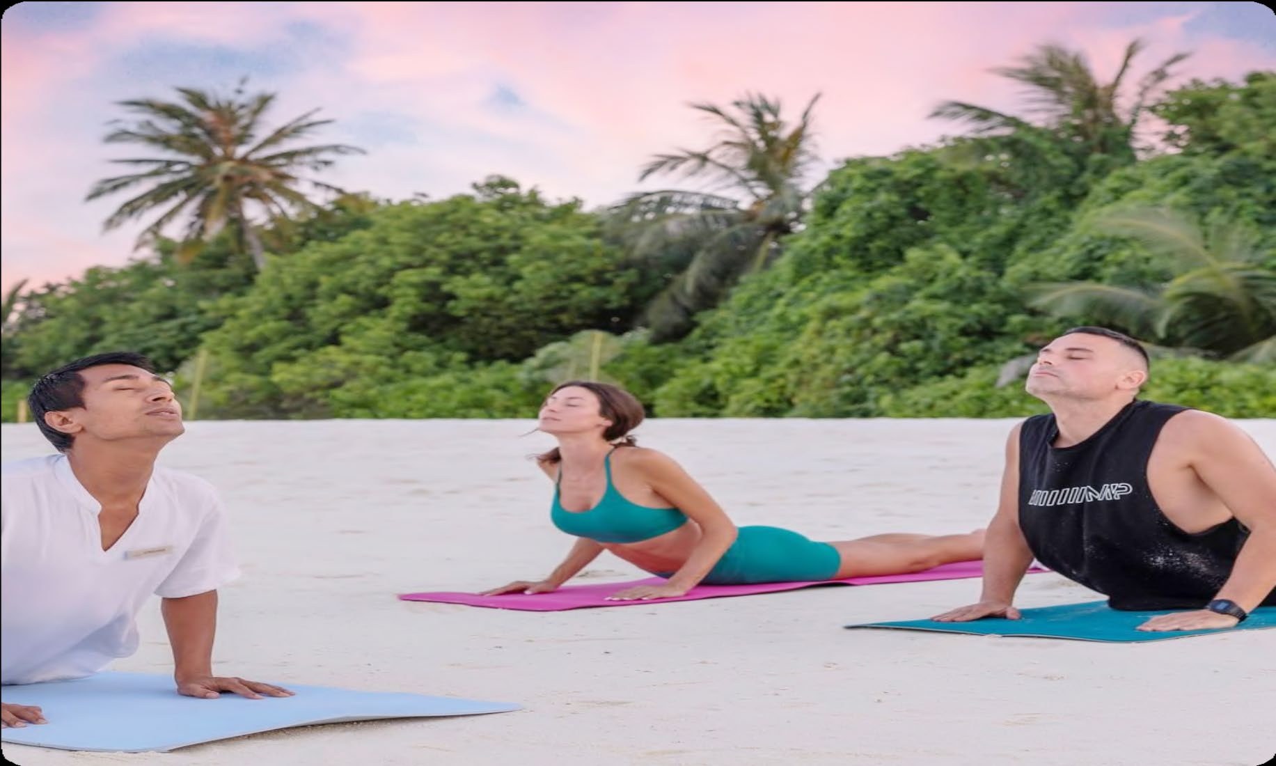 Guests practising yoga by the sea